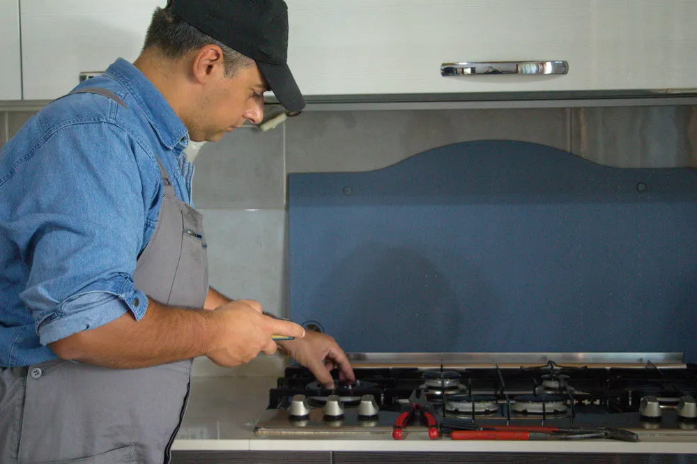 man stands front stove with blue apron that says gas it 1