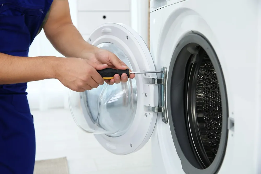 Dryer repair in Dubai - technician working on a tumble dryer door